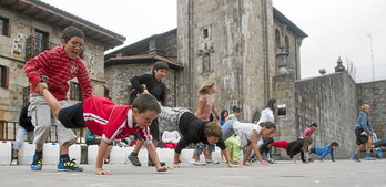 Haurrak jolasean, elizak eta pilotalekuak bat egiten duten Otxandioko plaza ederrean.