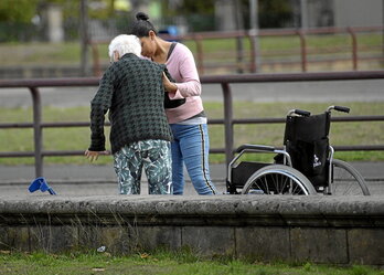 Zaintzaile bat adineko pertsona bati laguntzen.