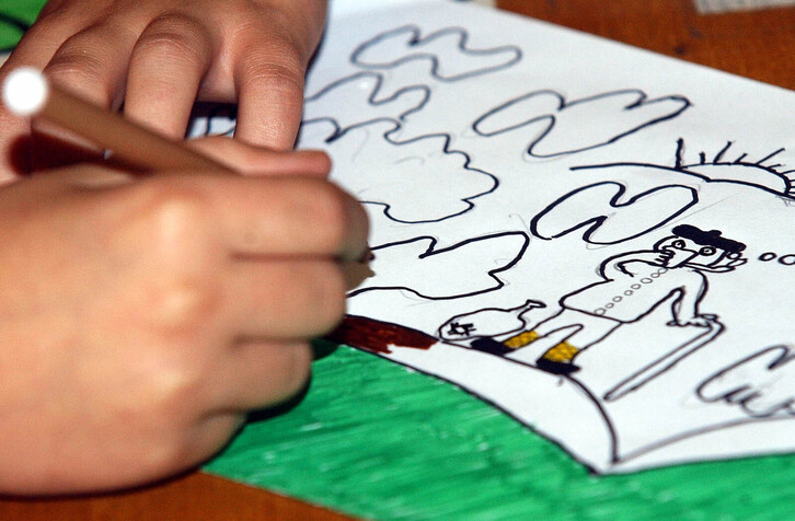 Haur bat marrazten, arxtiboko irudian.