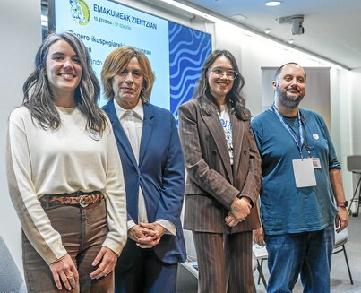 Lehen argazkian, ezkerretik eskuinera: Alejandra Patiño, Elena Aldasoro eta Irene Alonso, moderatzailearekin batera. Alboan, aretoaren irudi nagusia.